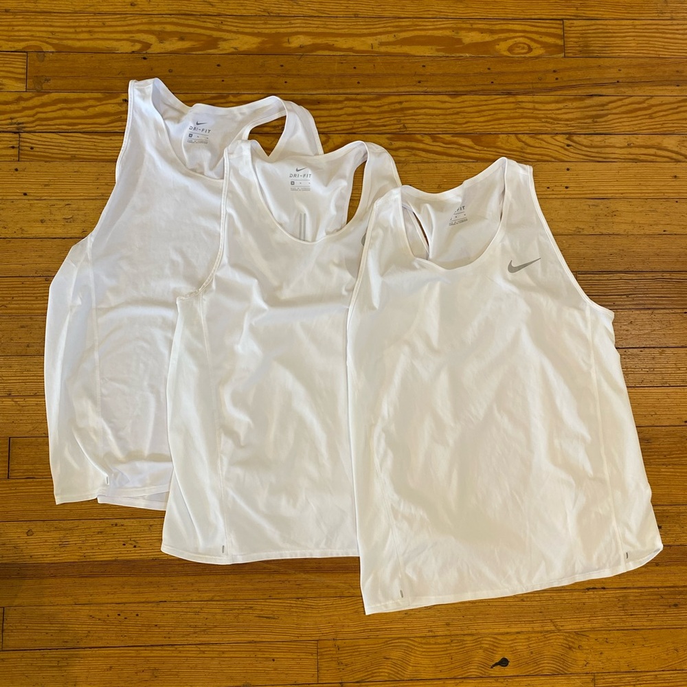 3 white Nike tanks